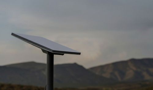 Antena parabólica rectangular de Starlink instalada en el exterior con montañas de fondo bajo un cielo nublado.