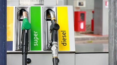Primer plano de mangueras en una gasolinera con etiquetas de combustible super y diesel.