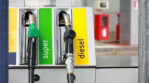 Primer plano de mangueras en una gasolinera con etiquetas de combustible super y diesel.