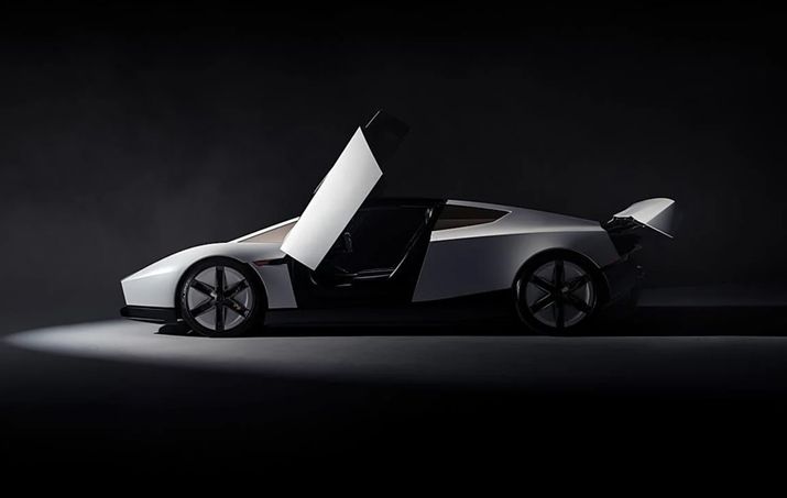 Vista lateral del Tesla Roadster blanco con una puerta abierta hacia arriba en un estudio oscuro.
