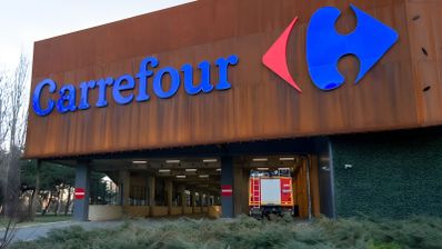 Fachada de un establecimiento Carrefour con un camión de bomberos estacionado en el acceso inferior.