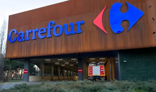 Fachada de un establecimiento Carrefour con un camión de bomberos estacionado en el acceso inferior.