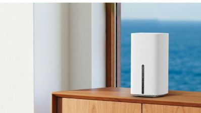 Router inalámbrico TP-Link Archer de color blanco con formato de torre vertical sobre un mueble de madera junto a una ventana.