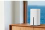 Router inalámbrico TP-Link Archer de color blanco con formato de torre vertical sobre un mueble de madera junto a una ventana.
