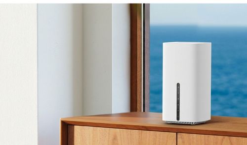 Router inalámbrico TP-Link Archer de color blanco con formato de torre vertical sobre un mueble de madera junto a una ventana.