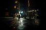 Operarios realizando tareas de mantenimiento en una calle durante la noche bajo focos de luz blanca.