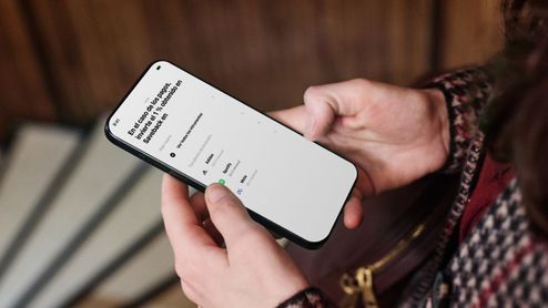 Persona sosteniendo un teléfono móvil con la interfaz de Trade Republic abierta mostrando opciones de inversión y ahorro.