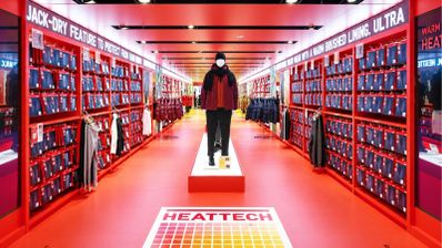 Interior de una tienda Uniqlo con pasillo central rodeado de estanterías rojas y productos Heattech.